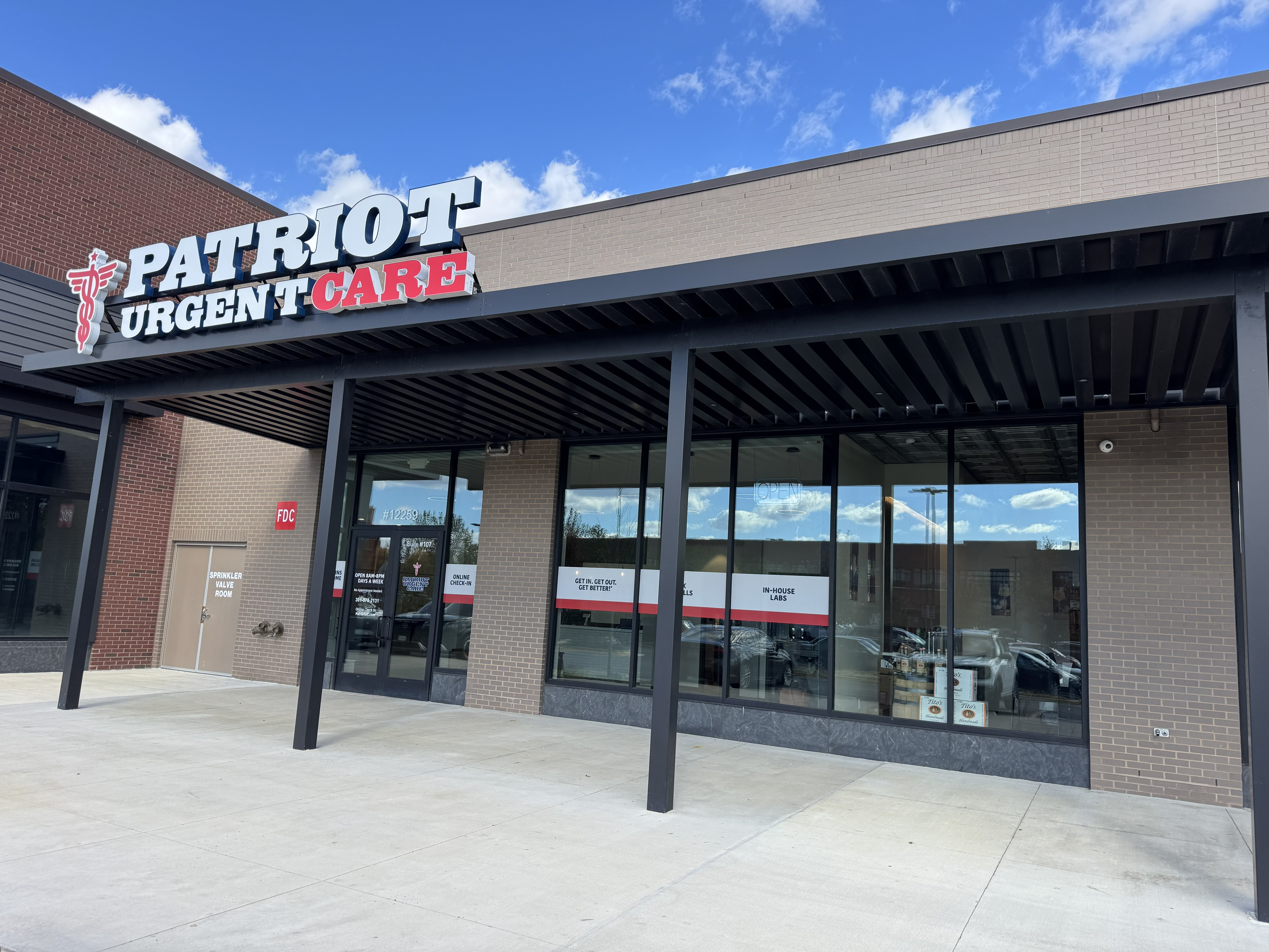 An exterior photo of the front entrance at Patriot Urgent Care in White Oak Town Center in Silver Spring, Maryland on a sunny day.